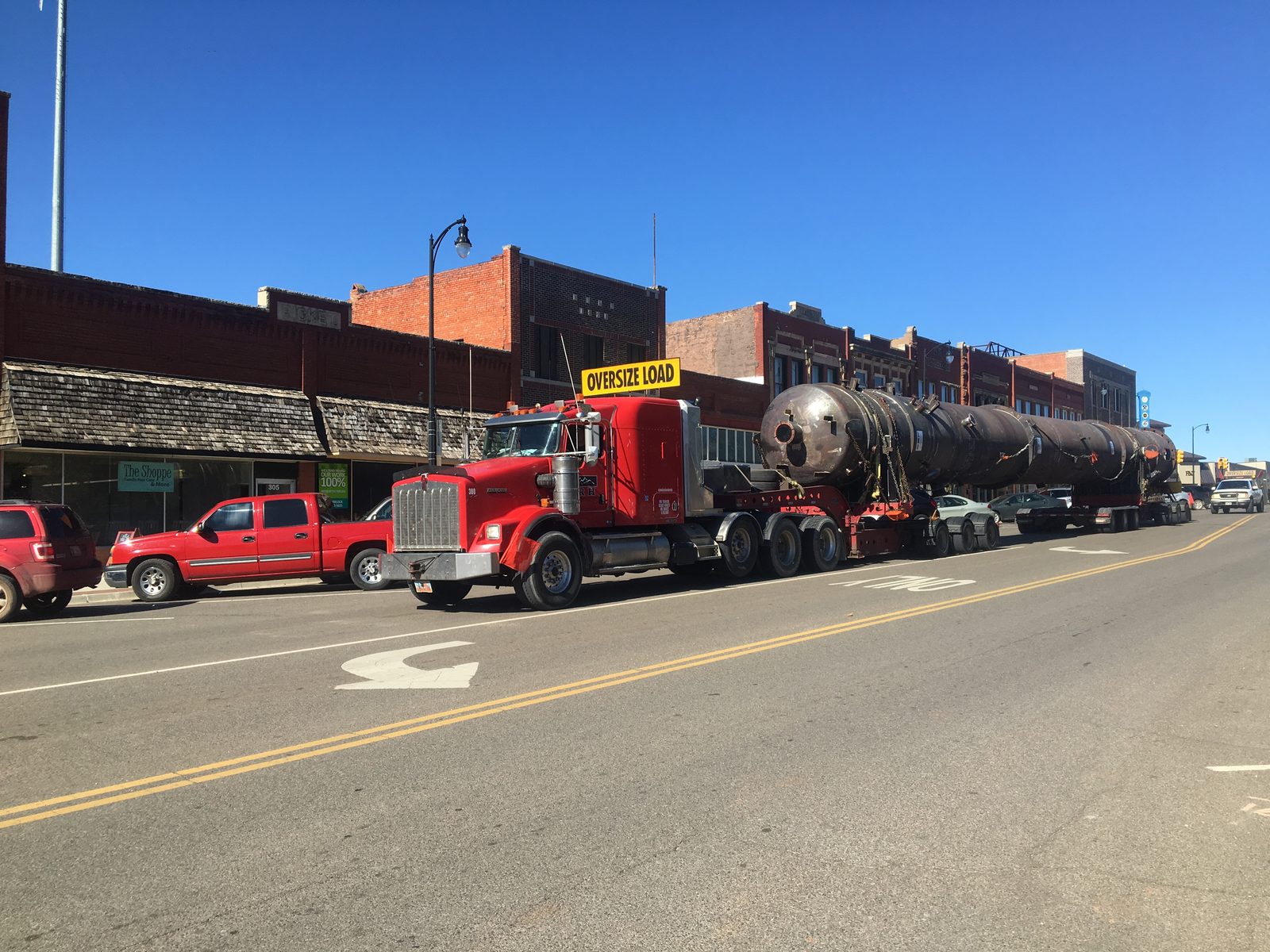 Long pressure vessel on stretch trailer moving through downtown Perry Oklahoma with oversize load sign